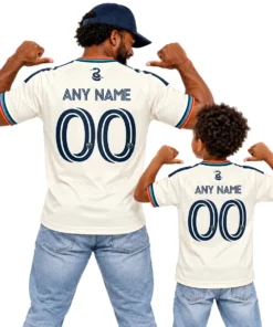 Father and son wearing matching cream Philadelphia Union third jerseys with multicolor sleeve trim